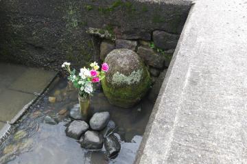 水路の中のお地蔵さまに花が飾られている様子です。