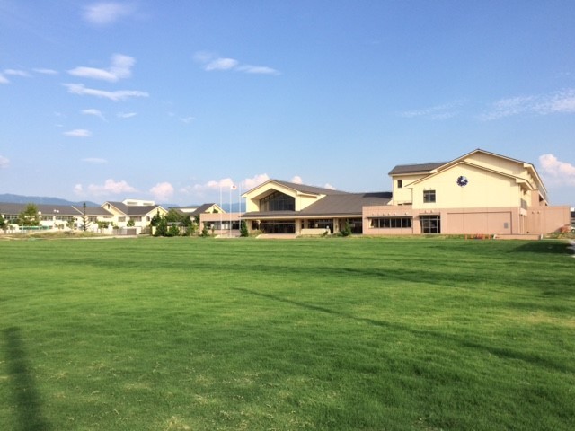八日市南小学校のグラウンド一面に緑の芝生が生えそろっている写真