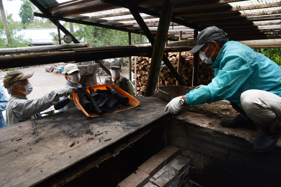 窯から焼いた炭を引き上げる男性