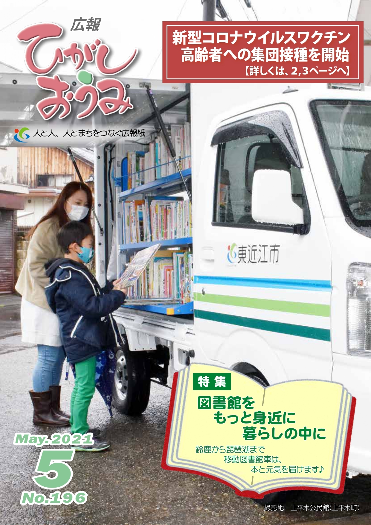 広報ひがしおうみ5月号の表紙。写真は上平木公民館で新しい移動図書館車を利用する親子の様子です。