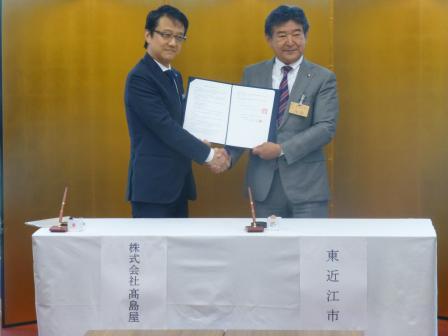 写真：高島屋の方と協定書をいっしょに持ち記念撮影する市長
