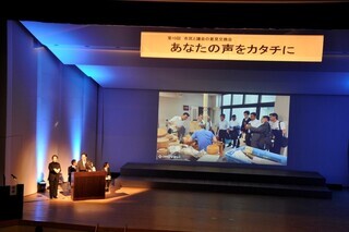 写真：ステージ上で行われた市議会の取組報告の様子2
