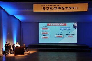 写真:ステージ上で行われた市議会の取組報告の様子1