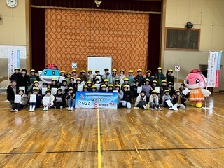 写真：体育館の舞台前で記念撮影をする布引小学校の児童たち