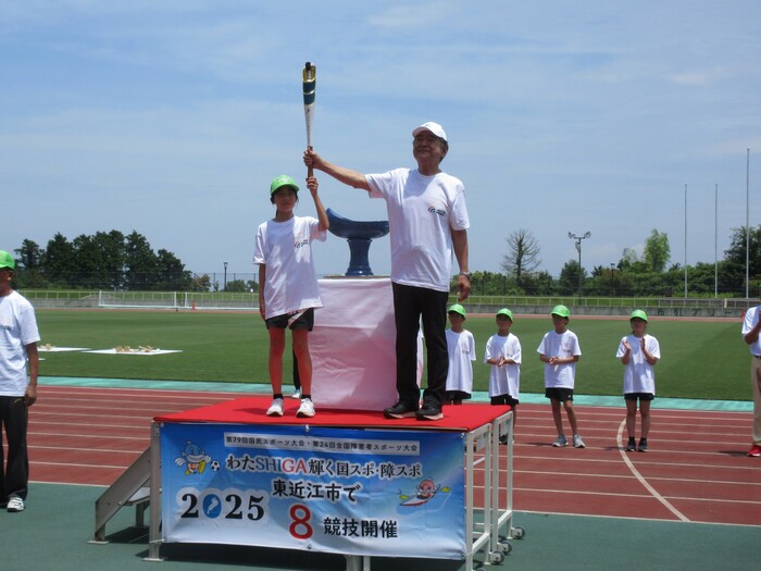 写真:炬火台前で小学生ランナーからトーチを受け取る市長