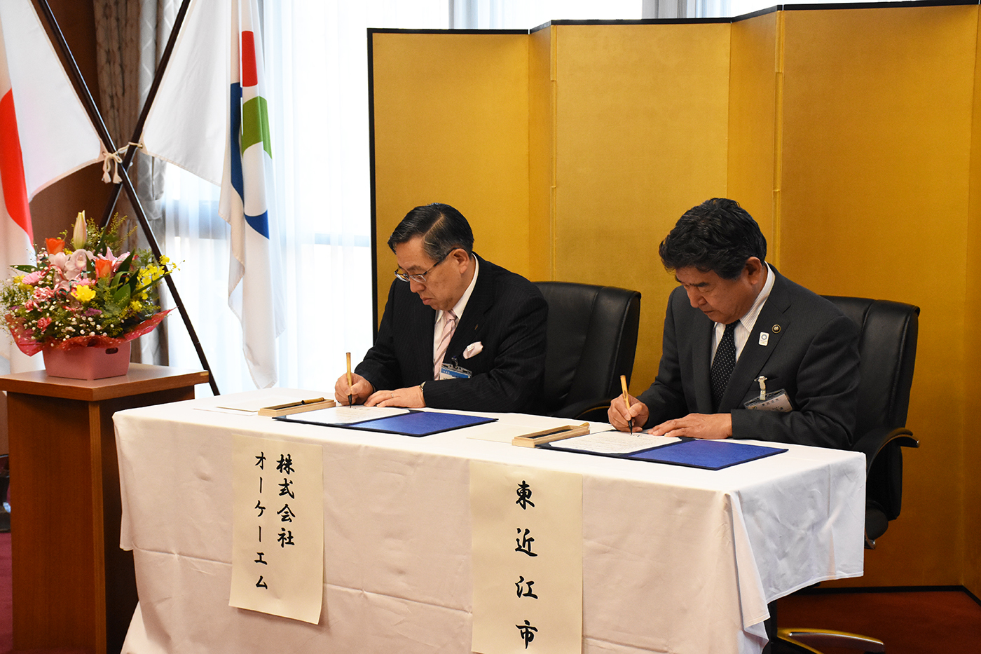協定書にサインする村井代表取締役会長と小椋市長